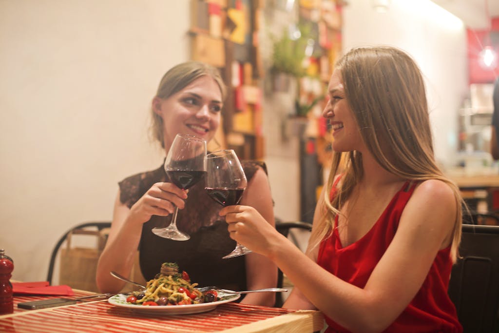 Two women sharing a joyful moment over dinner and wine at a cozy restaurant.